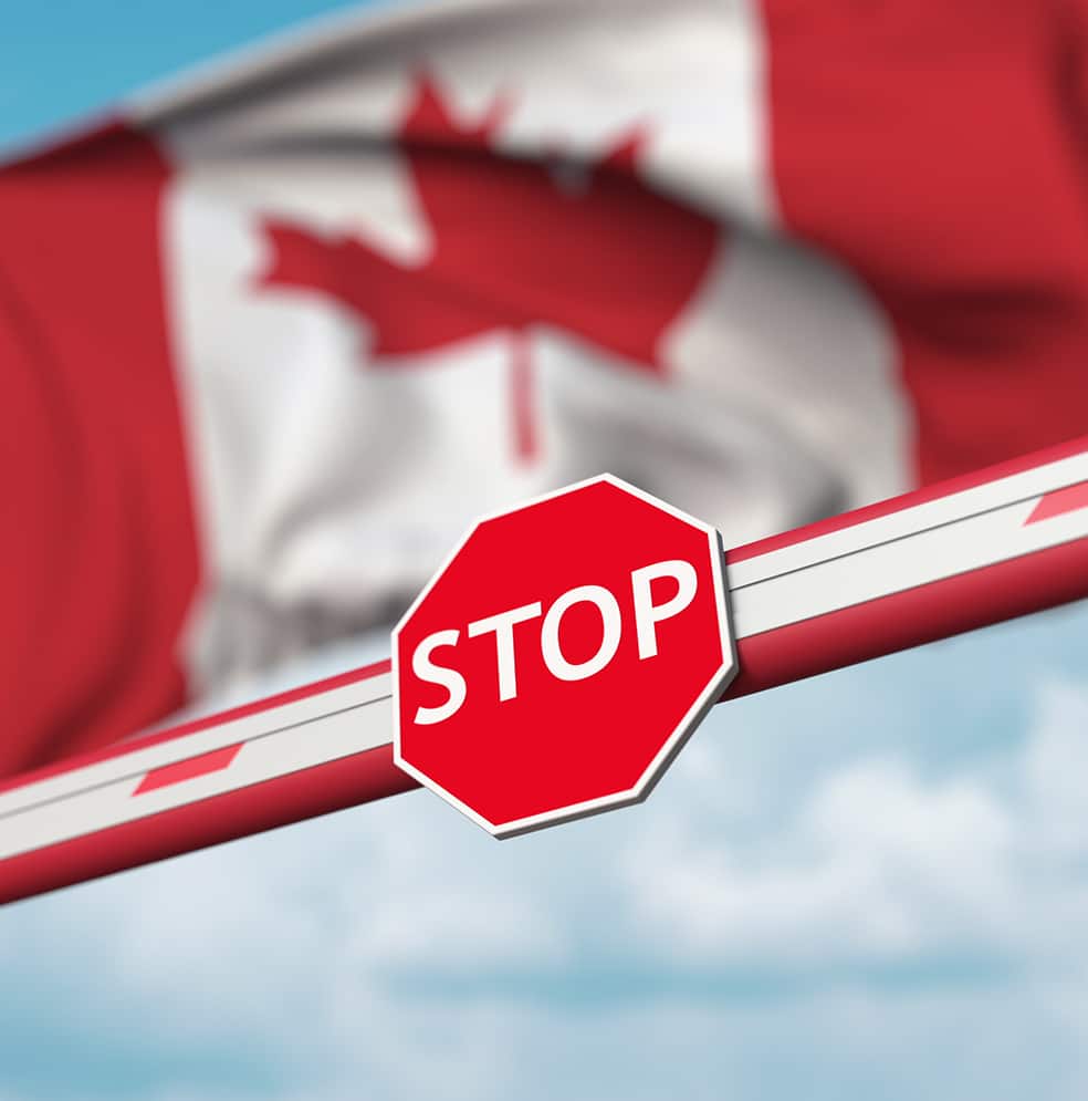 Image du dédouanement par Transport Bourassa avec une barrière affichant un panneau STOP et un drapeau du Canada en arrière-plan.